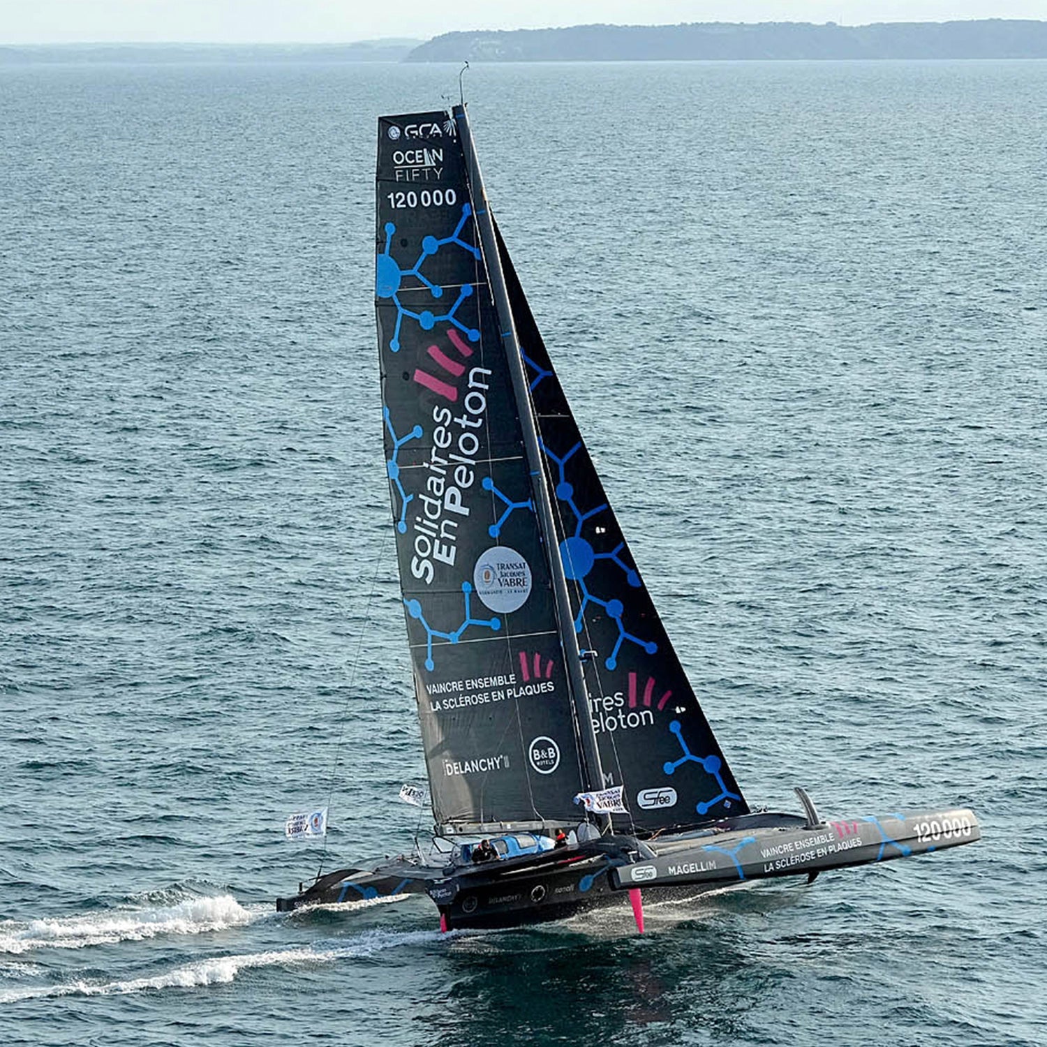 Thibaut Vauchel-Camus' vessel sails on a sunny day with blue skies and a blue ocean.//© Thibaut Vauchel Camus | Pierrick Contin