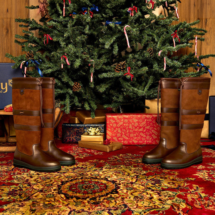 Square Image of a pair of Galway Leather Waterproof Breathable Country Boots positioned in front of a Christmas tree, with one pair on each side, creating a festive setting.//© Dubarry of Ireland